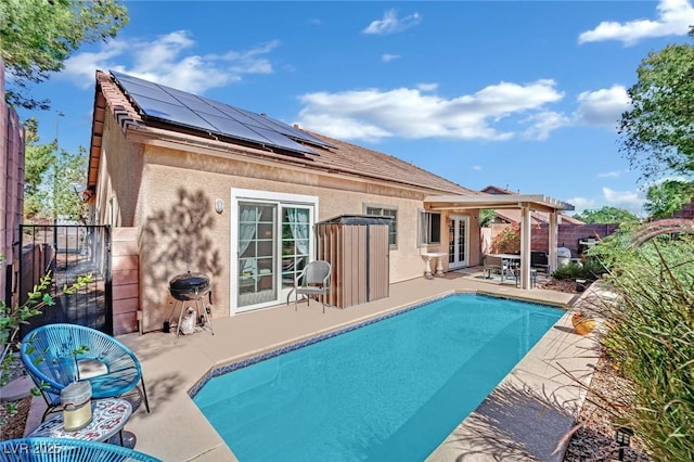 back of property featuring a fenced in pool, a patio area, and solar panels