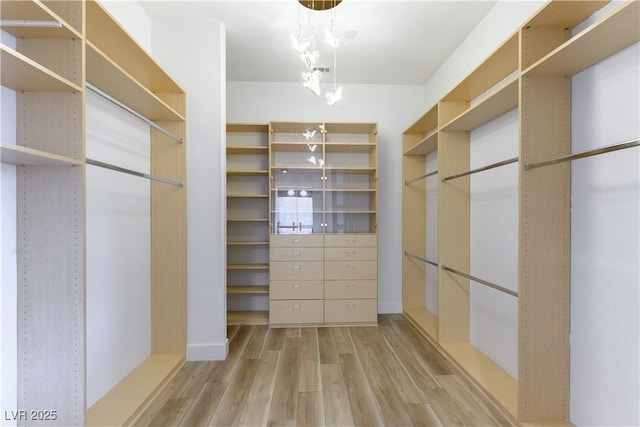 spacious closet with hardwood / wood-style flooring and a notable chandelier