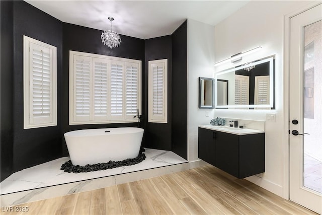 bathroom featuring vanity, a tub to relax in, wood-type flooring, and a chandelier