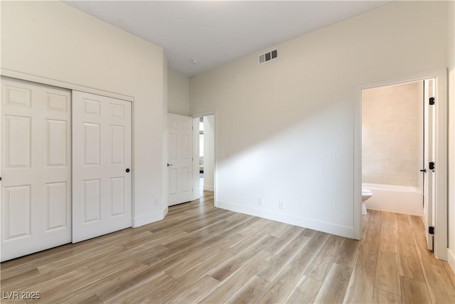 unfurnished bedroom with connected bathroom, light hardwood / wood-style floors, and a closet