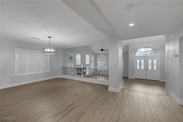 entryway with ceiling fan with notable chandelier, a healthy amount of sunlight, and hardwood / wood-style floors