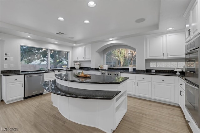 kitchen featuring light wood-type flooring, a kitchen island, white cabinets, and appliances with stainless steel finishes