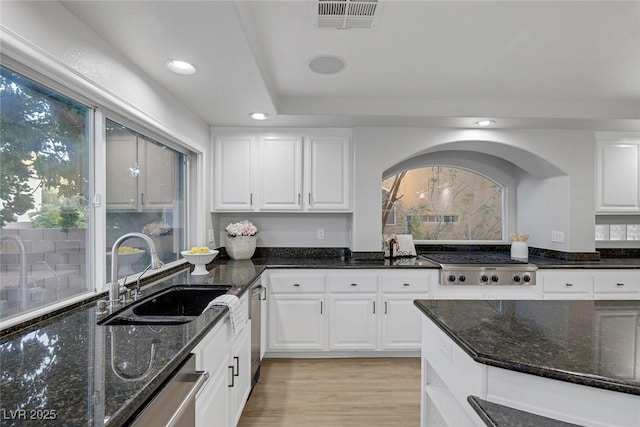 kitchen featuring sink, stainless steel appliances, dark stone counters, and white cabinets