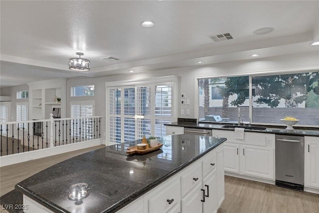 kitchen featuring dishwasher, white cabinetry, sink, dark stone countertops, and light hardwood / wood-style flooring