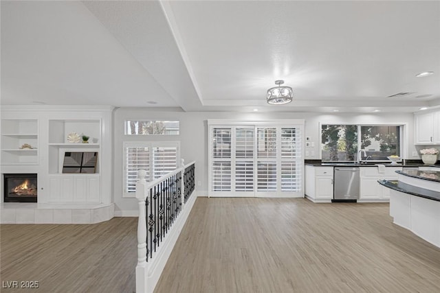 kitchen featuring sink, stainless steel dishwasher, built in features, light hardwood / wood-style floors, and white cabinets