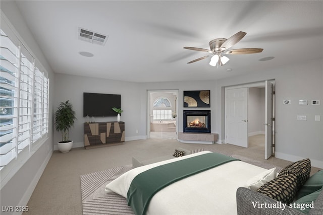 bedroom with light colored carpet, ensuite bathroom, ceiling fan, and a multi sided fireplace