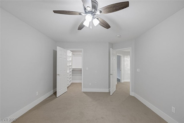 unfurnished bedroom featuring ceiling fan, a closet, light carpet, and a walk in closet