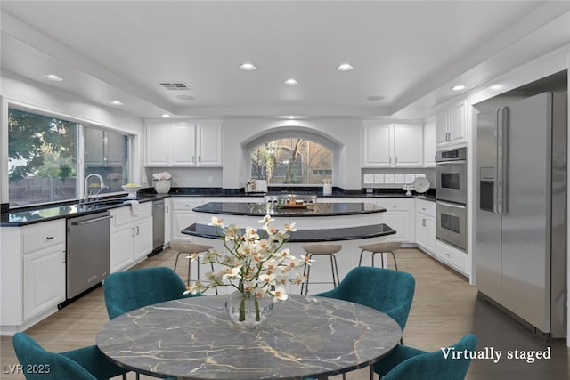 kitchen featuring sink, a raised ceiling, a kitchen island, stainless steel appliances, and white cabinets