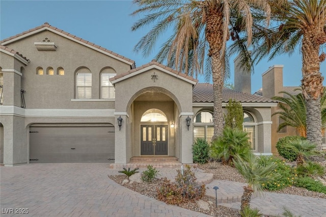 mediterranean / spanish-style house with a garage and french doors