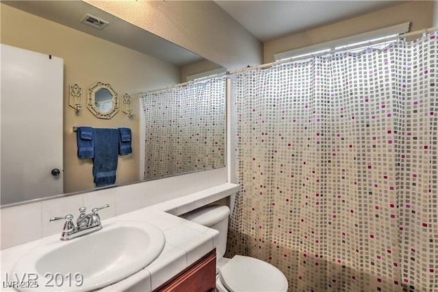 bathroom with vanity, decorative backsplash, and toilet