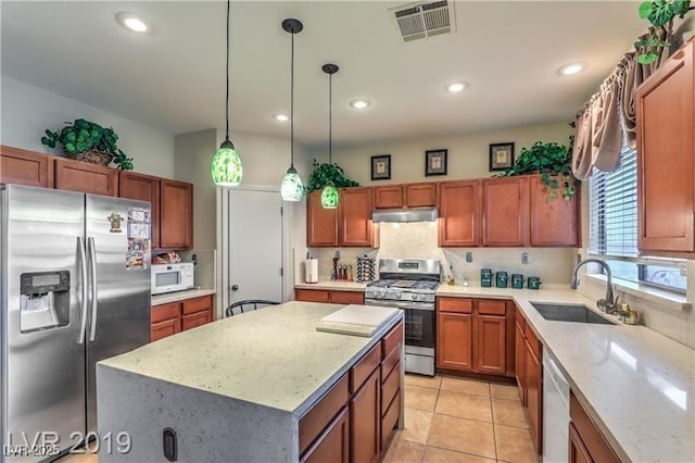 kitchen featuring a kitchen island, sink, backsplash, hanging light fixtures, and stainless steel appliances