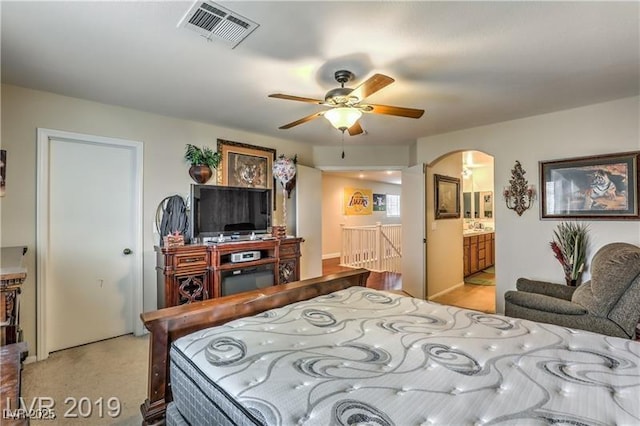 bedroom with light colored carpet, ceiling fan, and ensuite bathroom