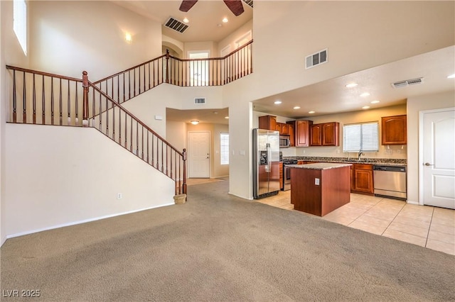 kitchen featuring light colored carpet, stainless steel appliances, a center island, and a wealth of natural light