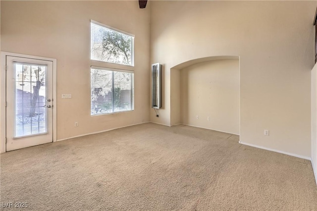 unfurnished living room with a towering ceiling and carpet floors