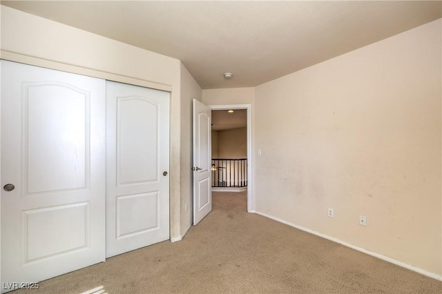 unfurnished bedroom featuring light carpet and a closet