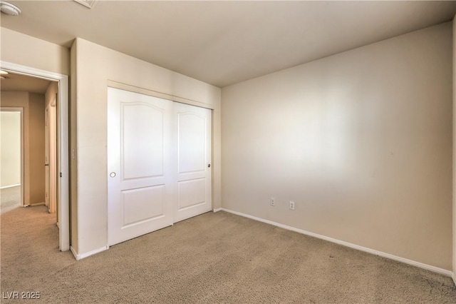 unfurnished bedroom featuring light carpet and a closet