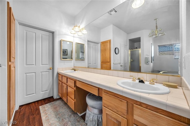 bathroom with an enclosed shower, vanity, hardwood / wood-style flooring, and an inviting chandelier