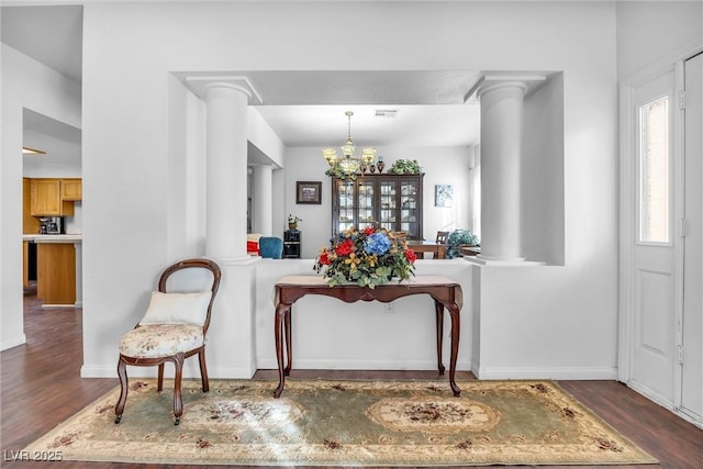 foyer entrance featuring dark hardwood / wood-style floors, decorative columns, and a wealth of natural light