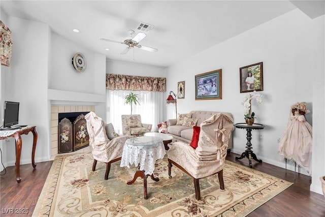 living room with ceiling fan, dark hardwood / wood-style floors, and a tile fireplace