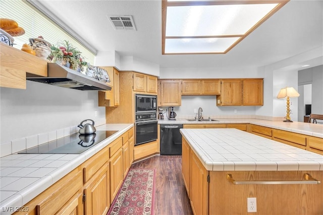 kitchen featuring sink, extractor fan, tile counters, black appliances, and a kitchen island