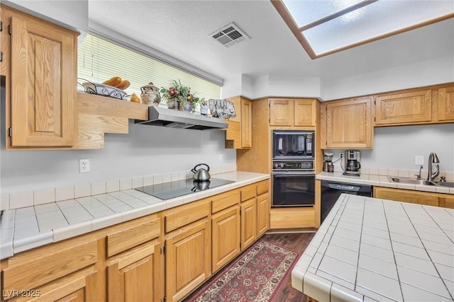 kitchen featuring sink, tile counters, dark hardwood / wood-style flooring, and black appliances