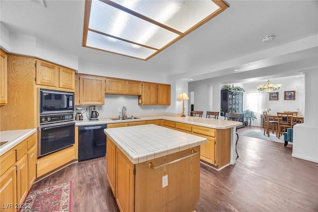 kitchen featuring sink, black appliances, kitchen peninsula, and a kitchen island