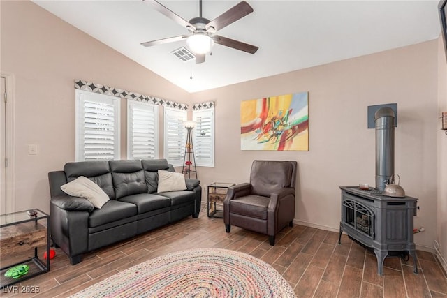 living room with vaulted ceiling, ceiling fan, and a wood stove