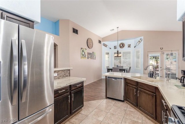 kitchen featuring lofted ceiling, sink, light tile patterned floors, appliances with stainless steel finishes, and pendant lighting