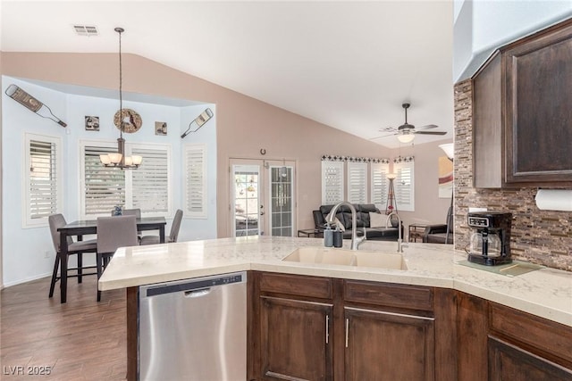 kitchen with sink, vaulted ceiling, stainless steel dishwasher, kitchen peninsula, and ceiling fan with notable chandelier