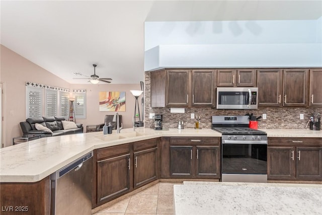 kitchen with sink, appliances with stainless steel finishes, backsplash, dark brown cabinetry, and kitchen peninsula