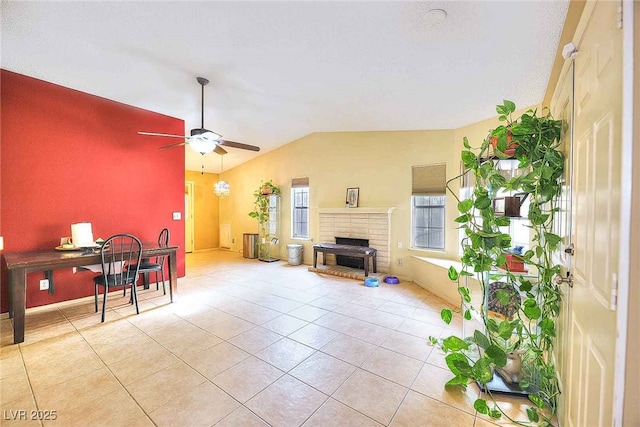 living room with light tile patterned flooring, ceiling fan, vaulted ceiling, and a brick fireplace