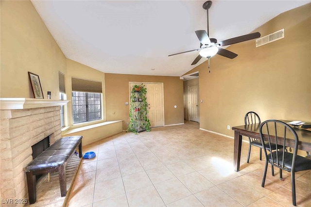 tiled living room featuring a fireplace and ceiling fan