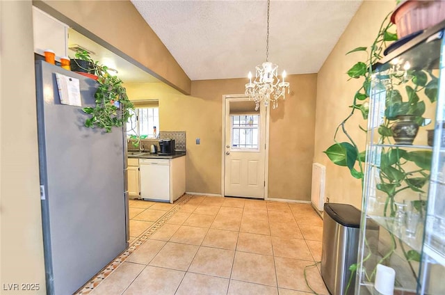 kitchen featuring light tile patterned floors, stainless steel fridge, dishwasher, white cabinetry, and a healthy amount of sunlight