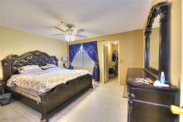 bedroom with ceiling fan, a spacious closet, a textured ceiling, and a closet