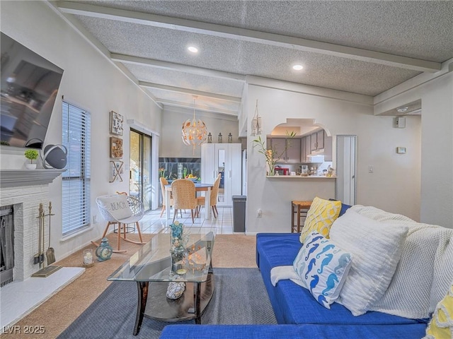 living room featuring beamed ceiling, a chandelier, a textured ceiling, and carpet