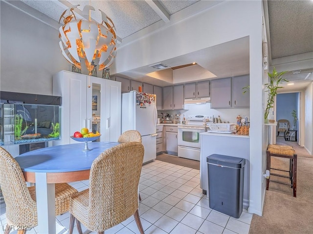 kitchen with gray cabinets, light tile patterned floors, a textured ceiling, and white appliances