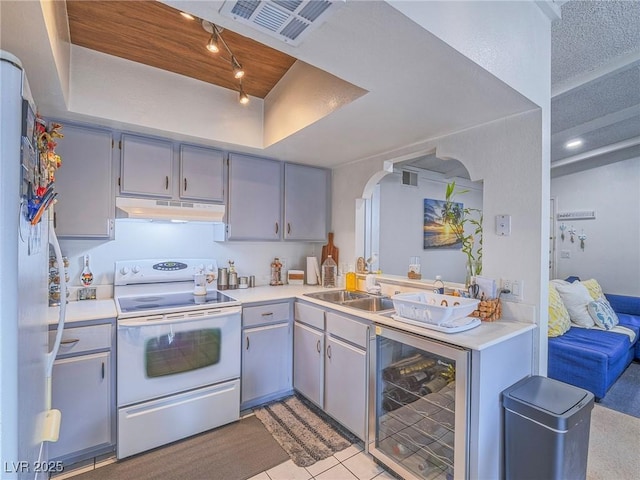 kitchen featuring gray cabinets, sink, beverage cooler, a raised ceiling, and white appliances