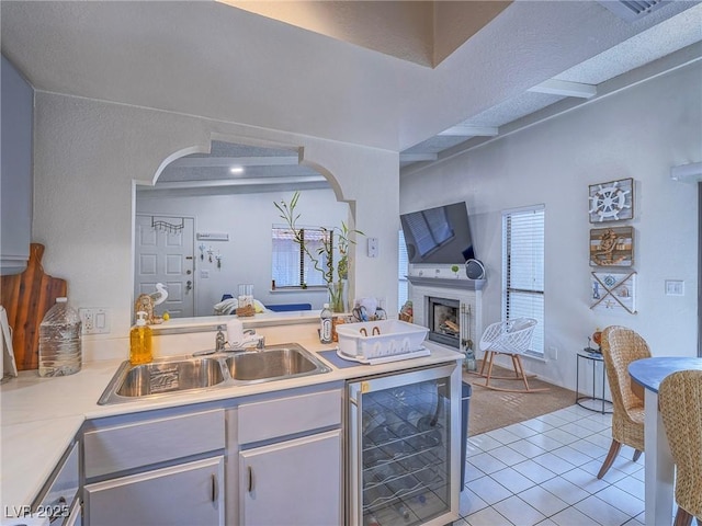 kitchen with sink, dishwasher, beam ceiling, wine cooler, and light tile patterned flooring