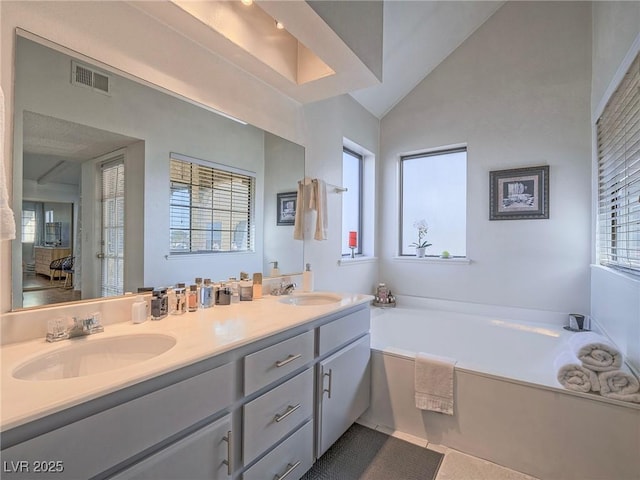 bathroom with vanity, lofted ceiling, and a tub