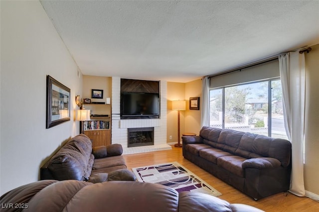 living room featuring a brick fireplace, light hardwood / wood-style flooring, and a textured ceiling