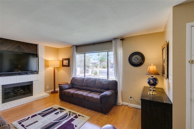 living room featuring a fireplace, light hardwood / wood-style floors, and a textured ceiling