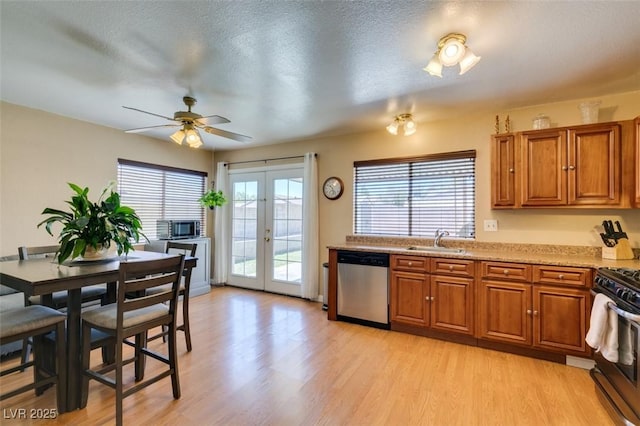 kitchen with sink, light hardwood / wood-style floors, stainless steel appliances, a textured ceiling, and french doors