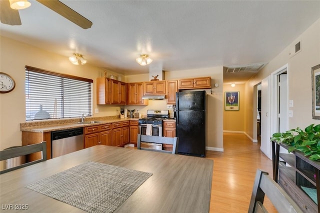 kitchen with ceiling fan, appliances with stainless steel finishes, sink, and light wood-type flooring