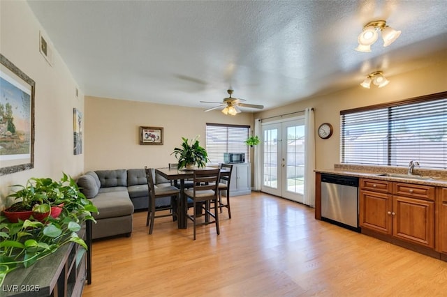 kitchen featuring sink, dishwasher, light hardwood / wood-style floors, a textured ceiling, and french doors