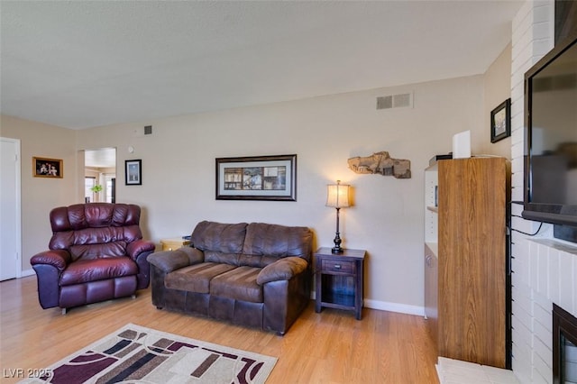 living room featuring a brick fireplace and light hardwood / wood-style flooring