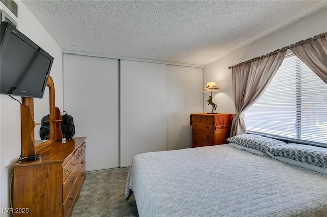 bedroom featuring dark carpet, a closet, and a textured ceiling