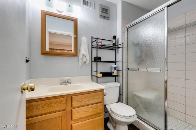 bathroom with vanity, toilet, and a shower with door