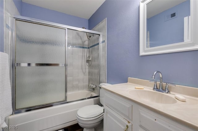 full bathroom with vanity, bath / shower combo with glass door, and toilet