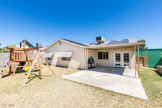 back of house with a playground, a patio, solar panels, central air condition unit, and french doors