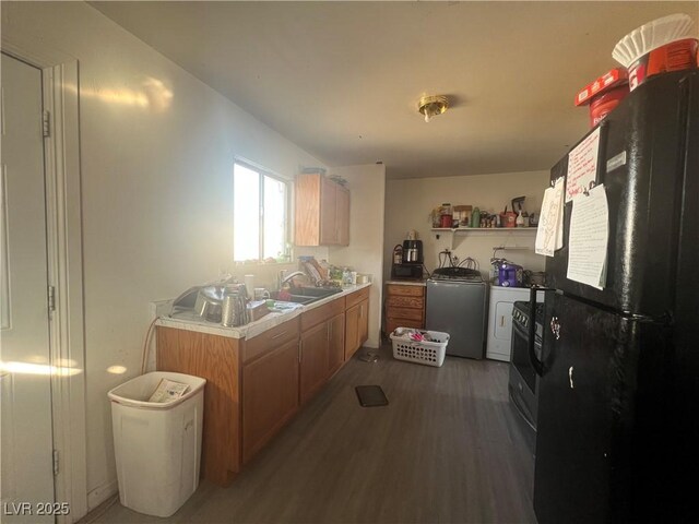 1900 W Carey Ave, North Las Vegas, NV 89032 - kitchen with sink, stainless steel gas stove, black fridge, dark hardwood / wood-style flooring, and washer / dryer